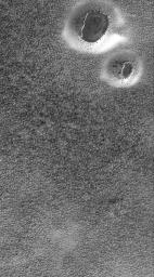 NASA's Mars Global Surveyor shows two circular features in the south polar region of Mars. The circular features are degraded impact craters. The dark, irregular features in each crater are the remnants of a layer of material.