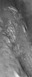 NASA's Mars Global Surveyor shows outcrops of light-toned, layered rock exposed in the central peak of Oudemans Crater, near the Labyrinthus Noctis of the western Valles Marineris complex on Mars.
