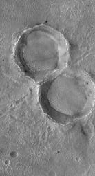 NASA's Mars Global Surveyor shows two craters that formed at the same time by a split meteoritic impactor. Long after they formed, these craters have been eroded, degraded, and other materials have been deposited on and within them.