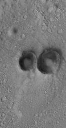 NASA's Mars Global Surveyor shows a pair of small meteor impact craters in the Arena Colles region of Mars, located north of Isidis Planitia.