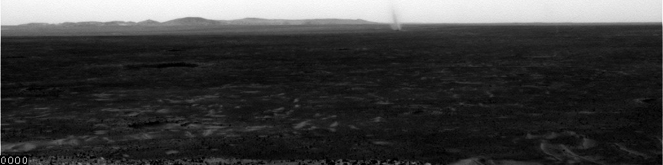 This image shows several dust devils moving from right to left across a plain inside Mars' Gusev Crater, as seen from the vantage point of NASA's Mars Exploration Rover Spirit in hills rising from the plain on July 13, 2005.