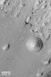 NASA's Mars Global Surveyor shows a stair-stepped mound of sedimentary rock on the floor of a large impact crater in western Arabia Terra on Mars. A circular mound and other nearby mesas and knobs are present.