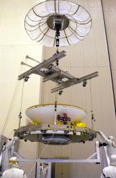 In the Payload Hazardous Servicing Facility, an overhead crane lowers the Mars Exploration Rover (MER) aeroshell toward a rotation stand.