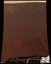 This color image in dark red hues shows the martian landscape at Meridiani Planum, where NASA's Mars Exploration Rover Opportunity successfully landed. A portion of the rover is in the foreground.