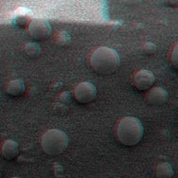 This 3-D anaglyph, from NASA's Mars Exploration Rover Spirit, shows a microscopic image taken of soil featuring round, blueberry-shaped rock formations on the crater floor at Meridiani Planum, Mars. 3D glasses are necessary to view this image.