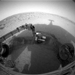 NASA's Mars Exploration Rover Spirit casts a shadow over the trench that the rover dug with its left front wheel and is examining with tools on its robotic arm. 