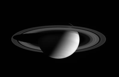 NASA's Cassini spacecraft wide angle camera view shows a half-lit Saturn, with two dark storms rolling through its southern hemisphere.