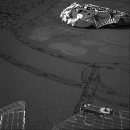 In this image, NASA's Mars Exploration Rover Opportunity is situated about about 20.3 feet from the lander. Rover tracks zig-zag along the surface. Bounce marks and airbag retraction marks are visible around the lander.