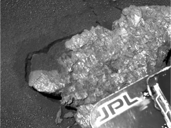 NASA's Mars Exploration Rover Opportunity took this image of the rock dubbed 'Bounce.' The rock has a number of shiny surfaces and textures on it. The Jet Propulsion Laboratory (JPL) logo is seen in the foreground.