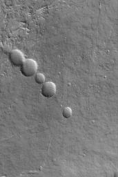 NASA's Mars Global Surveyor shows a chain of collapse pits on the lower northeast flank of the large martian volcano, Olympus Mons. 