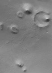 NASA's Mars Global Surveyor shows a summer scene from the south polar region of Mars. The circular feature in the northeast (upper right) corner of the image is an old meteor impact crater that has been partially filled and buried.