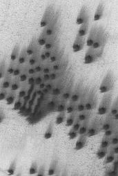 NASA's Mars Global Surveyor shows small, dark, north polar sand dunes and attendant wind streaks on Mars.
