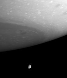 This dazzling view captured by NASA's Cassini spacecraft looks beyond gigantic storms near Saturn's south pole to the small but clear disc of Tethys (1,060 kilometers, or 659 miles, across).