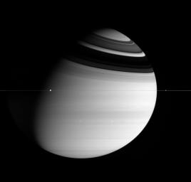 This image captured by NASA's Cassini spacecraft shows Dione and Enceladus orbit the mighty ringed planet Saturn, while two bright storms swirl in the atmosphere below.