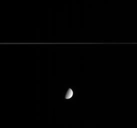 This image captured by NASA's Cassini spacecraft shows Saturn's crater-covered moon Tethys as it slid silently along in its orbit while Saturn's delicate rings sliced the view in two.