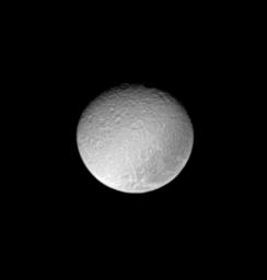 The ancient and battered surface of Saturn's moon Rhea shows a notable dark swath of territory near the eastern limb in this image from NASA's Cassini spacecraft.