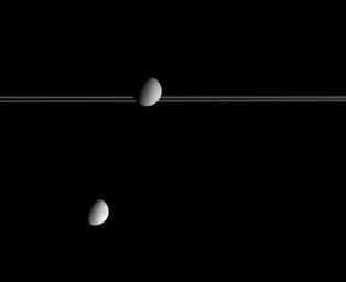 Saturn's moon Dione occults part of Saturn's distant rings while Tethys hovers below, as shown in this image captured by NASA's Cassini spacecraft.