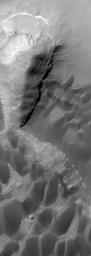 NASA's Mars Global Surveyor shows dark sand dunes and layered rock outcrops in Rabe Crater on Mars.