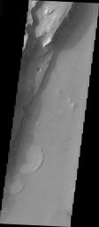 This image from NASA's Mars Odyssey shows landslides on Mars along a steep channel wall. The formation of the crater may have initially weakened an area of the surface prior to channel formation.