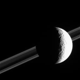 Saturn's brightly sunlit moon Rhea commands the foreground in this image from NASA's Cassini spacecraft.