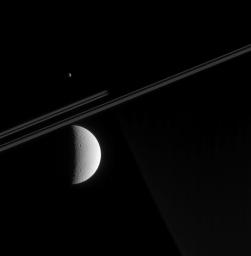 NASA's Cassini spacecraft looks toward Saturn's night side in this view, capturing a glimpse of Dione's tortured surface in the foreground and a far-off view of Epimetheus beyond Saturn.