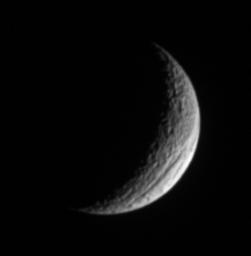 A crescent Tethys shows off its great scar, Ithaca Chasma, for which the moon is renowned. The lit surface visible here is on the moon's Saturn-facing hemisphere. This image is from NASA's Cassini spacecraft.