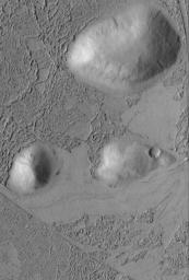 NASA's Mars Global Surveyor shows a plain covered by flow material that surrounded and banked against three older, rounded hills in the Zephyria region of Mars.