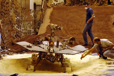 Rover engineers check how a test rover moves in material chosen to simulate some difficult Mars driving conditions. The scene is inside the In-Situ Instrument Laboratory at NASA's Jet Propulsion Laboratory, Pasadena, Calif. 