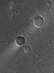This image from NASA's Mars Global Surveyor spacecraft shows two impact craters of nearly equal size, plus their associated wind streaks. These occur in far eastern Chryse Planitia.