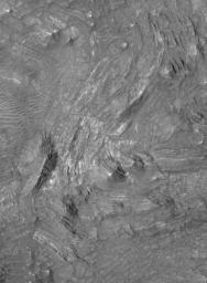 NASA's Mars Global Surveyor shows light-toned, layered rock outcrops in the central pit of an impact crater in the Thaumasia Planum region of Mars. The outcrops were tilted and broken-up by the extreme energy of the impact that formed the crater.