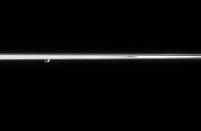 Janus peeks out from beneath the ringplane, partially lit here by reflected light from Saturn. A couple of craters can be seen on the moon's surface. At right, two faint clumps of material are seen in the dynamic F ring in this image from NASA's Cassini.