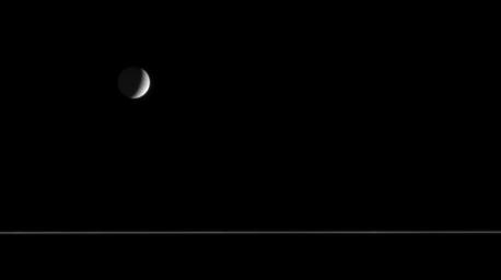 Quiet and cold, a crescent Tethys floats above the nearly edge-on rings of Saturn. The only surface features visible to NASA's Cassini spacecraft on Tethys from this distance are a few impact craters.