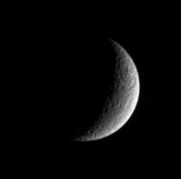A prominent scar on Rhea is seen by NASA's Cassini. A large and ancient impact basin is seen at upper right. The giant feature occurs within a terrain that appears rugged and which likely is saturated with other smaller craters.