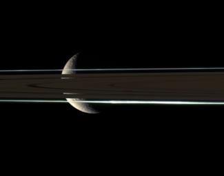 The rings cannot hide the ragged, icy crescent of Rhea, here imaged in color by NASA's Cassini spacecraft. The second-largest moon of Saturn shines brightly through gaps in the rings