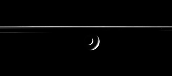 The bright crescent of Saturn's moon Enceladus slides past distant Rhea in this mutual event, or occultation, in this image from NASA's Cassini spacecraft.