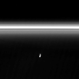 The moon Prometheus slowly collides with the diffuse inner edge of Saturn's F ring in image from NASA's Cassini spacecraft. The oblong moon pulls a streamer of material from the ring and leaves behind a dark channel.