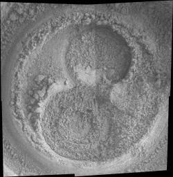 This image shows two shallow, circular holes - one above and one below - that meet in the middle to form an indentation shaped like a figure eight in the Martian soil. The holes are within a larger circular area created by the rock abrasion tool