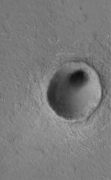 NASA's Mars Global Surveyor shows some a modest-sized meteor impact crater in the Elysium Planitia region of Mars. The dark spot inside the crater is, most likely, a patch of windblown sand and silt.