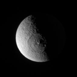 NASA's Cassini spacecraft stares directly into the great Odysseus impact basin on Tethys. Peaks near the crater's center cast long shadows toward the east. The elevated eastern rim of the crater catches sunlight.