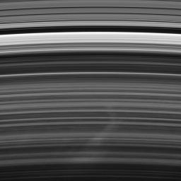 A bright spoke extends across the unilluminated side of Saturn's B ring about the same distance as that from London to Cairo. The background ring material displays some azimuthal asymmetry as seen by NASA's Cassini spacecraft.