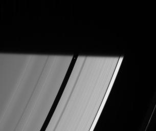Pan prepares to be engulfed by the darkness of Saturn's shadow, visible here as it stretches across the rings as seen by NASA's Cassini spacecraft.