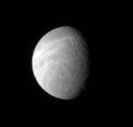Wispy markings reach out across Rhea's surface from its trailing hemisphere. The bright markings appear to be fractures, like those found on Dione