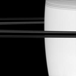 Off the shoulder of giant Saturn, a bright pinpoint marks the location of the ring moon Atlas (image center). Shadows cast by the C ring adorn the planet at upper right as seen by NASA's Cassini spacecraft.