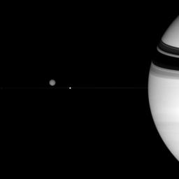 Three of Saturn's diverse family of moons are captured in this view from NASA's Cassini spacecraft. Titan hovers above the thin line of the rings. Epimetheus is a mere speck at far left. Enceladus sits in front of the ringplane from Cassini's view.