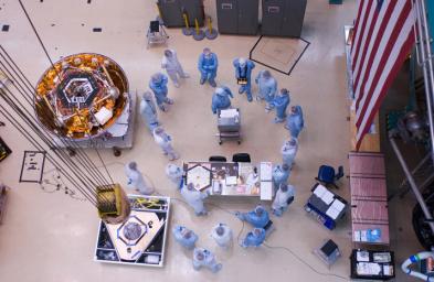 Spacecraft specialists huddle to discuss the critical lift of NASA's Phoenix Mars Lander into a thermal vacuum chamber.