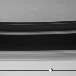 The moon Tethys cruises past, in front of Saturn's edge-on rings. The rings cast threadlike shadows onto the northern hemisphere of the planet. This image was taken by NASA's Cassini spacecraft.