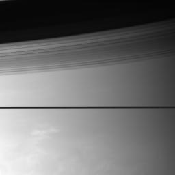 Saturn's rings divide this scene, casting graceful shadows onto the planet. Below, bright clouds hint at the turbulent world beneath the haze. This image was taken by NASA's Cassini spacecraft.