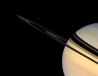 Saturn's icy satellites, Tethys, Mimas, Janus, and Pandora wheel about the colorful giant planet, while the rings shine dimly in scattered sunlight in this image captured by NASA's Cassini spacecraft on Oct. 30, 2007.