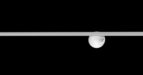 Saturn's rings slice across this scene, obscuring the cracked face of Dione. This image was taken in visible light with NASA's Cassini spacecraft's narrow-angle camera on Jan. 17, 2008.