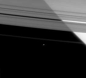 Saturn's brilliant limb shines through the semi-transparent A ring, while the outer F ring shepherd moon, Pandora, hangs against the black sky in this image from NASA's Cassini spacecraft taken on Apr. 5, 2008.